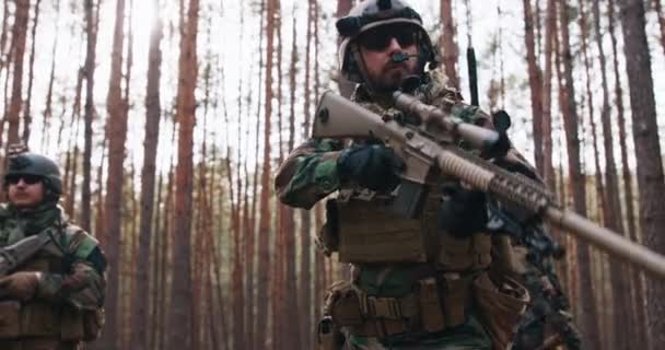 Soldados de mediana edad totalmente equipados que usan uniformes de camuflaje atacando al enemigo en posición de disparo apuntando a rifles Operación militar en acción Escuadrón de pie en un bosque denso — Vídeos de Stock