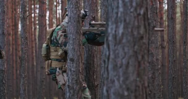 Voll ausgerüstete Soldaten in Tarnuniform greifen Feindgewehre in Schussposition an Militäroperation in Formation, die mittags durch dichten Wald läuft — Stockvideo