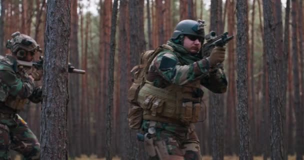 Soldados totalmente equipados con uniforme de camuflaje atacando rifles enemigos en posición de disparo Operación militar en acción Escuadrón en formación a través del denso bosque al mediodía — Vídeos de Stock