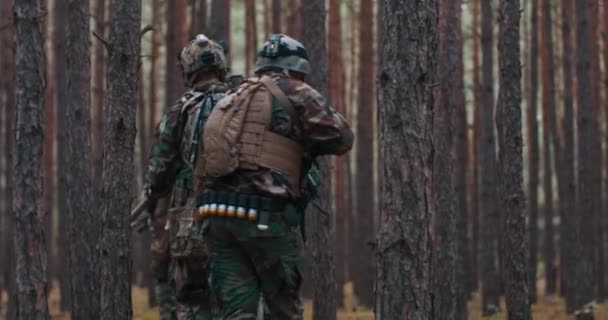 Trupp av soldater under militär operation fullt utrustade kamouflage på en rekognoscering militära uppdrag gevär i skottläge De kör i formation genom tät skog — Stockvideo