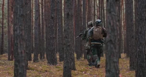 Eenheid soldaten tijdens militaire operatie volledig uitgerust camouflage op een verkenningsmissie geweren in vuurpositie ze rennen in formatie door dichte bossen — Stockvideo