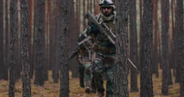 Vier voll ausgerüstete Soldaten mittleren Alters in Tarnuniformen bilden eine abschussbereite Linie mit ihren Gewehren Eine Militäroperation im Einsatz eine Einheit, die in einem dichten Wald steht — Stockvideo