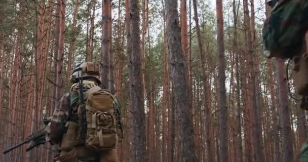 Fullt utrustade soldater bär kamouflage enhetlig attack fiendens gevär i eldgivning position militär operation i aktion truppen vistas i Bildning genom tät skog vid middagstid — Stockvideo