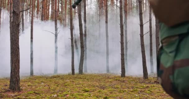 Plně vybavených vojáků pohybující se kouřovým lesem s puškou připraven střílet průzkumné vojenské operace oddíl pohybující se za ním borovicový les — Stock video