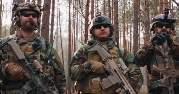 Trupp av fullt utrustade soldater i kamouflage stå i tät tallskog spaning militära uppdrag — Stockvideo