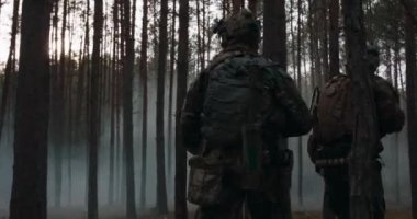 Tam teçhizatlı askerler, harekattan dönüyorlar. Bir askeri operasyon. Karanlık, dumanlı bir ormanın içinde yürüyen bir birlik.