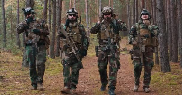 Soldados totalmente equipados en uniforme de camuflaje regresando de un reconocimiento en un bosque de pinos — Vídeos de Stock