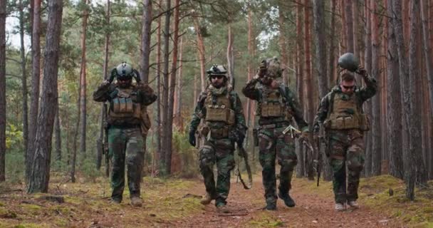 Fullt utrustade soldater i kamouflage uniform återvänder från spaning i en tallskog — Stockvideo