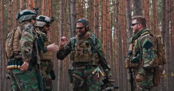 身着迷彩服、装备齐全的士兵们正在森林里享受着完成的任务。他们笑着高高兴兴 — 图库视频影像