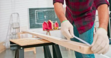 Bir marangoz atölyesindeki tahtayı ölçerken elinde cetvel ve kalem tutan çalışkan bir marangozun yakın çekimi. Sakallı bir DIY meraklısı odunları ölçer.