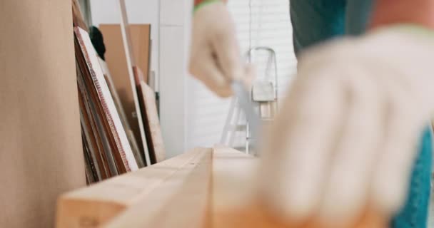 Gros plan d'un menuisier professionnel qui travaille dur tenant une règle et un crayon tout en mesurant une planche dans un atelier de menuiserie. Un amateur de bricolage barbu mesure le bois. — Video