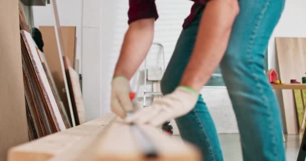 Detailní záběr pilně pracujícího profesionálního tesaře držícího pravítko a tužku při měření desky v truhlářské dílně Vousatý milovník kutilství měří dřevo — Stock video