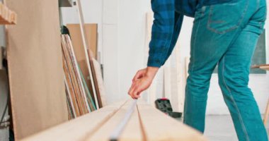 Bir marangoz atölyesindeki kirişi ölçerken elinde cetvel ve kalem tutan çalışkan profesyonel marangoz sakallı bir DIY meraklısı odunu ölçer.