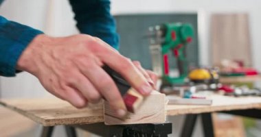 Sakallı bir tamirci marangozluk atölyesinde mobilya için ahşap zımparalıyor.