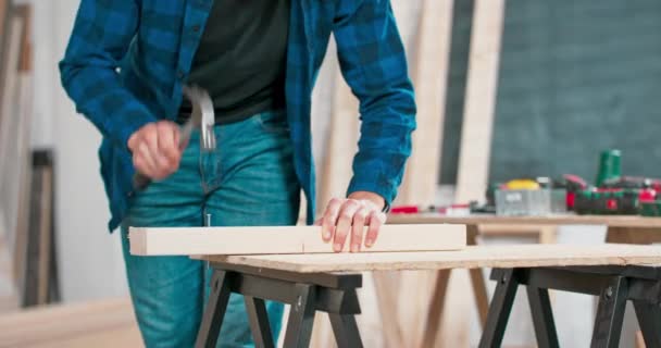 Primo piano di martellare un chiodo a bordo Un falegname che indossa una camicia rossa di flanella jeans e guanti di protezione panno inchioda le tavole di legno — Video Stock