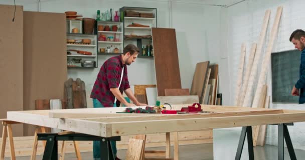 Νεαροί ξυλουργοί χτίζουν έναν συμπαγή τοίχο από ξύλο σε εργαστήριο ξυλουργικής — Αρχείο Βίντεο