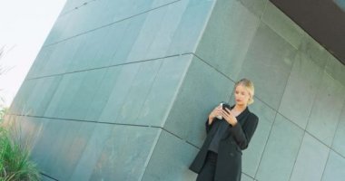 Avukat - genç beyaz kadın avukat cep telefonuna bakıyor ve tek kullanımlık kahve içiyor.