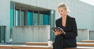 İş kadını dışarıda, önde, sosyal iletişim teknolojisinde dijital tablet kullanır ve oturur.
