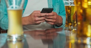 Adam bir bardaki akıllı telefondan bir mesaj yazıyor.