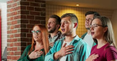 Beyaz erkek ve kadın arkadaşlar sporun başında milli marşı izlerken barda hareketsiz duruyorlar.