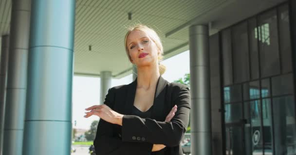 Формально одетая американская деловая женщина смотрит в камеру со скрещенными руками, стоя — стоковое видео