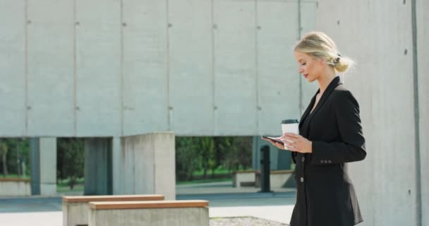 Mooie vrouw gaat om te werken met koffie wandelen in de buurt van kantoor gebouw Portret van succesvolle zaken — Stockvideo