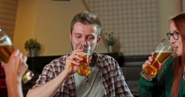 Друзья смеются, пьют пиво и коктейли, веселятся вместе в баре — стоковое видео