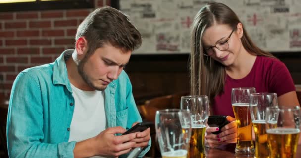 Pár gépel egy üzenetet egy okostelefonon egy bárban, miközben egy pohár — Stock videók