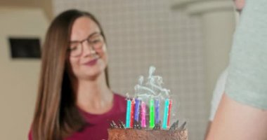 Genç ve güzel bir kadın doğum günü pastasında dilek diliyor ve mumları üflüyor.