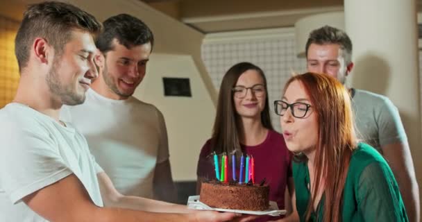 Jovem mulher bonita está fazendo desejo e soprando velas no bolo de aniversário enquanto celebra — Vídeo de Stock