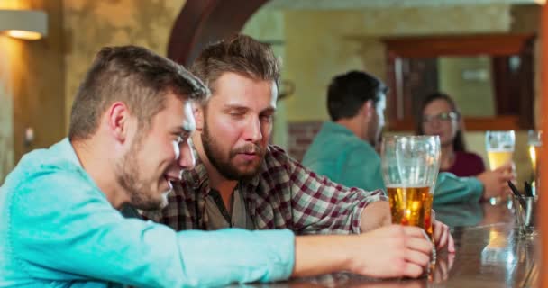 Unbekümmert lächelnde Freunde genießen das gemeinsame Trinken in einer Bar Gruppe fröhlicher junger Männer, die kalt trinken — Stockvideo