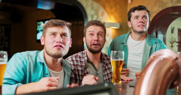 Chłopaki, fani piłki nożnej oglądają mecz wieczorem w pubie i martwią się o swoje — Wideo stockowe