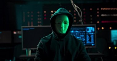 Veri 'nin ortasında oturan maskeli bir hackerın yakın plan fotoğrafı.