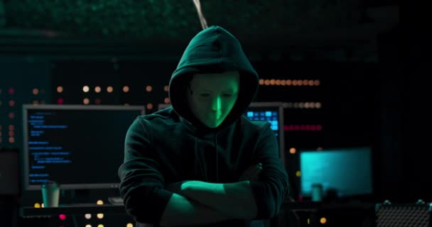 Close-up shot van een gemaskerde hacker in een hoodie zittend in het midden van de gegevens — Stockvideo