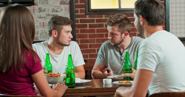 Compañía de amigos divirtiéndose en el bar, beben, hablan y bromean alrededor de hermosa — Vídeos de Stock