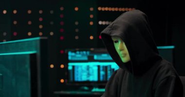 Maskeli ve kapüşonlu anonim bilgisayar korsanı karanlık yüzü siber saldırı için bilgisayar kullanarak gizledi.