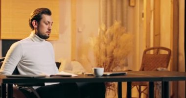 Tekerlekli sandalyede beyaz balıkçı yakalı yakışıklı engelli adam çatı katında çalışıyor.