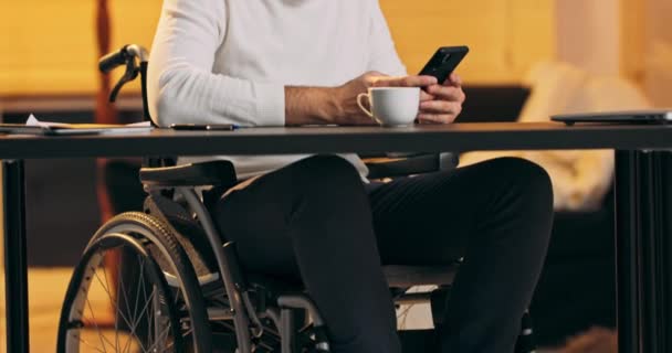 Hombre millennial en silla de ruedas celebración de mensajes de texto de teléfonos inteligentes modernos en la oficina Joven hombre de negocios utilizando útil — Vídeos de Stock
