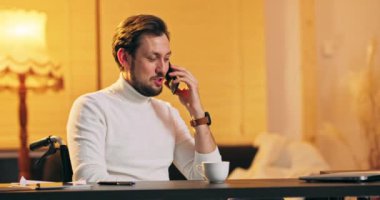 Tekerlekli sandalyede sakallı, orta yaşlı bir adam çatı katında oturuyor ve iletişim kuruyor.