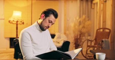 Genç engelli adam kitap okuyor. Sınıfta tekerlekli sandalyede oturuyor. Amerikan manzarası var.