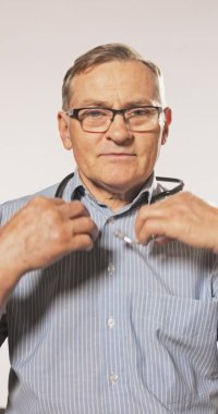 Olgun, yaşlı bir doktor. Gömlek ve gözlük takıyor. Hastaları kabul etmeye hazırlanıyor.