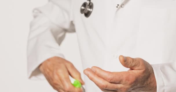 Пожилой врач, одетый в белый фартук, достает антибактериальный гель для рук — стоковое видео