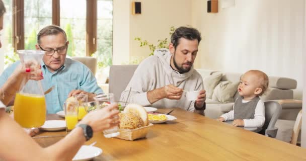 一家人在家里的饭桌边吃早餐一个男人坐在一个小餐馆里喂他的小儿子。 — 图库视频影像