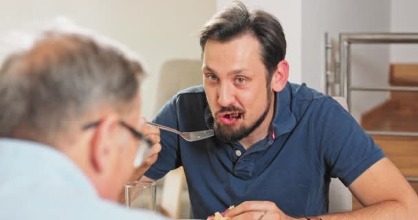 Padre e hijo desayunando juntos en el comedor, hablando, chico comiendo ensalada preparada por — Vídeo de stock