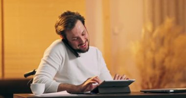 İyi bakımlı sakallı, modern görünümlü genç adam kazadan sonra tekerlekli sandalyede oturuyor ve uzaktan...