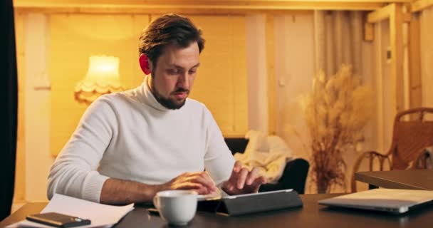 El hombre de mediana edad con discapacidad concentrada se sienta en una silla de ruedas escribiendo en una tableta digital, disfruta usando — Vídeos de Stock