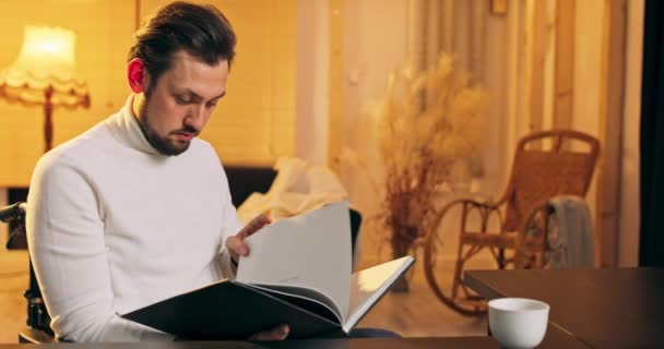 Portrét muže středního věku vousatý běloch v invalidním vozíku čtení knihy doma invalidní muž — Stock video