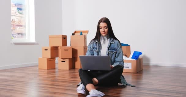 Felice giovane donna caucasica seduta sul pavimento in un nuovo appartamento e pensando al futuro — Video Stock