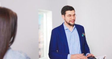 Neşeli beyaz erkek emlakçı Amerikalı genç evli çifte yeni bir daire gösteriyor.