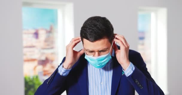 Gros plan d'un jeune homme caucasien gestionnaire d'agence immobilière revêtant un visage médical protecteur — Video
